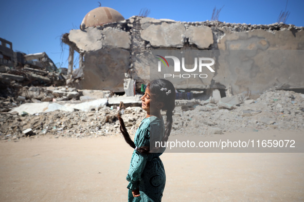 A Palestinian girl walks beside a mosque after it is bombed in an Israeli airstrike in Khan Younis, southern Gaza Strip, on October 12, 2024...