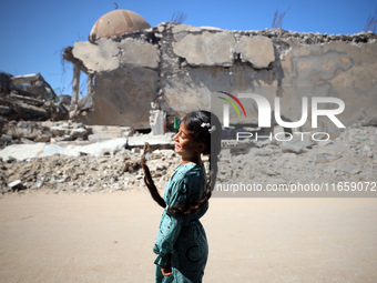 A Palestinian girl walks beside a mosque after it is bombed in an Israeli airstrike in Khan Younis, southern Gaza Strip, on October 12, 2024...