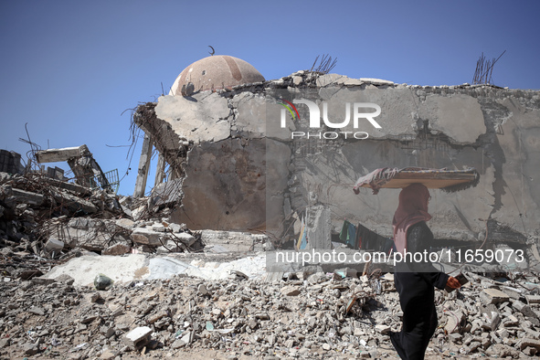 A Palestinian woman walks beside a mosque after it is bombed in an Israeli airstrike in Khan Younis, southern Gaza Strip, on October 12, 202...