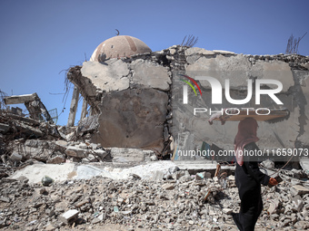 A Palestinian woman walks beside a mosque after it is bombed in an Israeli airstrike in Khan Younis, southern Gaza Strip, on October 12, 202...