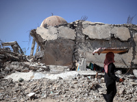 A Palestinian woman walks beside a mosque after it is bombed in an Israeli airstrike in Khan Younis, southern Gaza Strip, on October 12, 202...