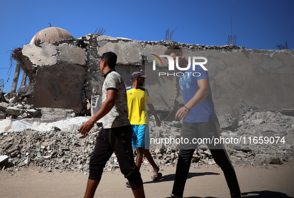 Palestinians walk past a mosque after it is hit in an Israeli strike in Khan Younis, in the southern Gaza Strip, on October 12, 2024, amid t...