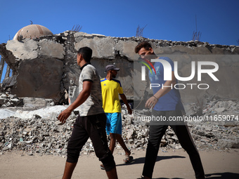 Palestinians walk past a mosque after it is hit in an Israeli strike in Khan Younis, in the southern Gaza Strip, on October 12, 2024, amid t...