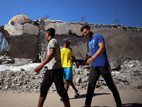 Palestinians walk past a mosque after it is hit in an Israeli strike in Khan Younis, in the southern Gaza Strip, on October 12, 2024, amid t...