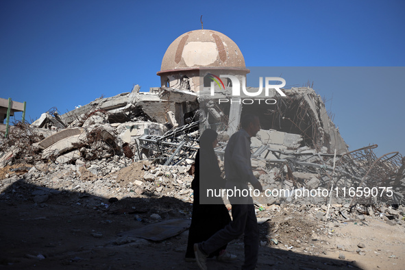 Palestinians walk past a mosque after it is hit in an Israeli strike in Khan Younis, in the southern Gaza Strip, on October 12, 2024, amid t...