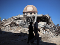 Palestinians walk past a mosque after it is hit in an Israeli strike in Khan Younis, in the southern Gaza Strip, on October 12, 2024, amid t...