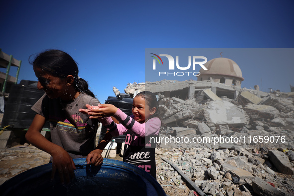 Palestinian girls play with water beside a mosque after it is bombed in an Israeli airstrike in Khan Younis, southern Gaza Strip, on October...