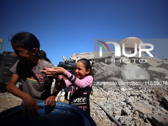 Palestinian girls play with water beside a mosque after it is bombed in an Israeli airstrike in Khan Younis, southern Gaza Strip, on October...