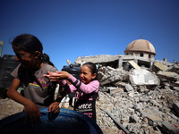 Palestinian girls play with water beside a mosque after it is bombed in an Israeli airstrike in Khan Younis, southern Gaza Strip, on October...