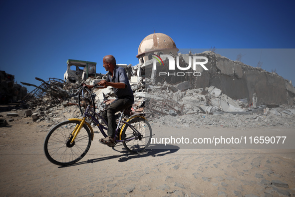 A Palestinian man rides a bicycle beside a mosque after it is bombed in an Israeli airstrike in Khan Younis, southern Gaza Strip, on October...