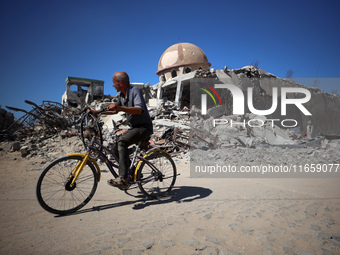 A Palestinian man rides a bicycle beside a mosque after it is bombed in an Israeli airstrike in Khan Younis, southern Gaza Strip, on October...