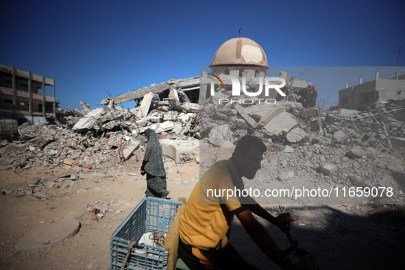 Palestinians walk past a mosque after it is hit in an Israeli strike in Khan Younis, in the southern Gaza Strip, on October 12, 2024, amid t...