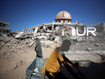 Palestinians walk past a mosque after it is hit in an Israeli strike in Khan Younis, in the southern Gaza Strip, on October 12, 2024, amid t...