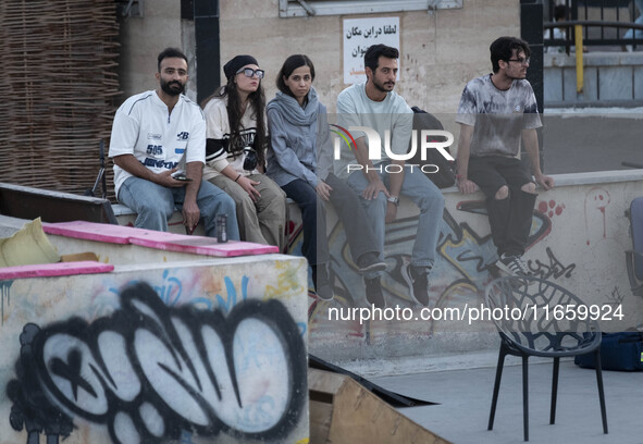 Iranian youths sit together while waiting to watch a freestyle bicycle competition at the Navid BMX Bike Park in southern Tehran, Iran, on O...