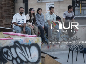 Iranian youths sit together while waiting to watch a freestyle bicycle competition at the Navid BMX Bike Park in southern Tehran, Iran, on O...