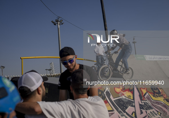 Young Iranian men stand together while two female participants wait to perform in a freestyle bicycle competition at the Navid BMX Bike Park...