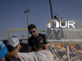 Young Iranian men stand together while two female participants wait to perform in a freestyle bicycle competition at the Navid BMX Bike Park...