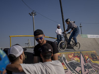 Young Iranian men stand together while two female participants wait to perform in a freestyle bicycle competition at the Navid BMX Bike Park...