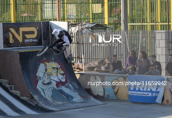 Young Iranian men watch a young woman perform in a freestyle bicycle competition at the Navid BMX Bike Park in southern Tehran, Iran, on Oct...