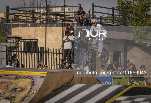 Iranian youths watch a young woman perform in a freestyle bicycle competition at the Navid BMX Bike Park in southern Tehran, Iran, on Octobe...