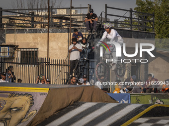 Iranian youths watch a young woman perform in a freestyle bicycle competition at the Navid BMX Bike Park in southern Tehran, Iran, on Octobe...