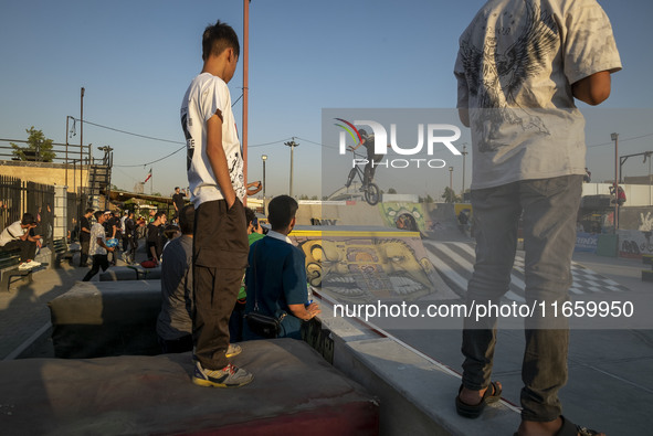 Iranian youths watch a participant perform in a freestyle bicycle competition at the Navid BMX Bike Park in southern Tehran, Iran, on Octobe...