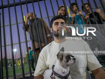 An Iranian man hugs his pet while watching a freestyle bicycle competition at the Navid BMX Bike Park in southern Tehran, Iran, on October 1...