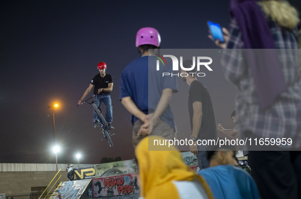 Iranian youths watch a participant perform in a freestyle bicycle competition at the Navid BMX Bike Park in southern Tehran, Iran, on Octobe...