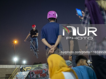 Iranian youths watch a participant perform in a freestyle bicycle competition at the Navid BMX Bike Park in southern Tehran, Iran, on Octobe...