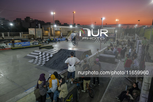 Iranian youths watch a participant perform in a freestyle bicycle competition at the Navid BMX Bike Park in southern Tehran, Iran, on Octobe...