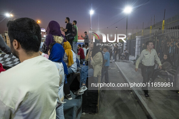 An Iranian policeman monitors an area while youths watch a freestyle bicycle competition at the Navid BMX Bike Park in southern Tehran, Iran...