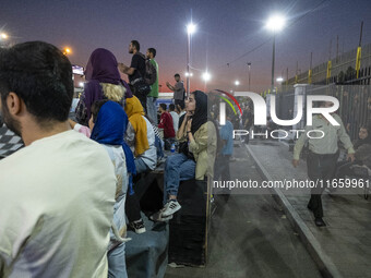 An Iranian policeman monitors an area while youths watch a freestyle bicycle competition at the Navid BMX Bike Park in southern Tehran, Iran...