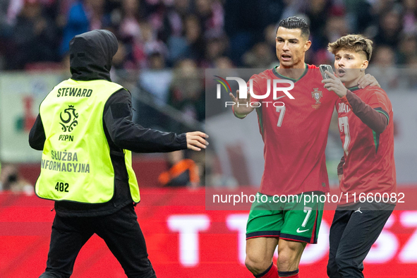 A pitch invader takes a selfie photograph with Portugal forward Cristiano Ronaldo during the  UEFA Nations League 2024 League A Group A1 mat...