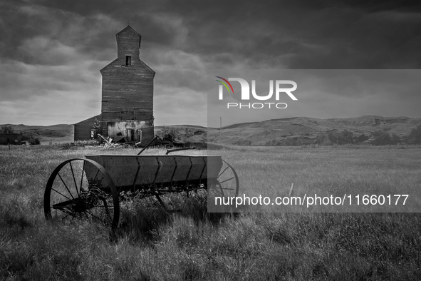 A seed spreader sits in front of an abandoned grain elevator in the ghost town of Owanka, South Dakota, USA. 