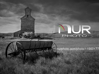 A seed spreader sits in front of an abandoned grain elevator in the ghost town of Owanka, South Dakota, USA. (