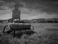 A seed spreader sits in front of an abandoned grain elevator in the ghost town of Owanka, South Dakota, USA. (