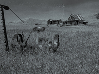 A horse-drawn sickle bar sits in front of an abandoned farm in the ghost town of Owanka, South Dakota, USA. (