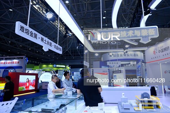 Visitors visit the booths of insoluble metals and rare earth permanent magnets at the 9th China Advanced Materials Industry Expo 2024 in Qin...