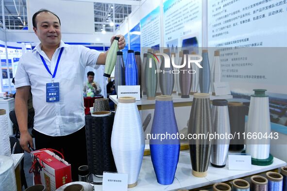 An exhibitor displays a body of colored glass fiber materials at the 9th China Advanced Materials Industry Expo 2024 in Qingdao, China, on O...