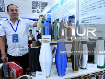 An exhibitor displays a body of colored glass fiber materials at the 9th China Advanced Materials Industry Expo 2024 in Qingdao, China, on O...