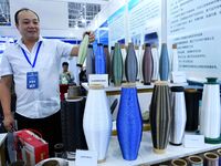 An exhibitor displays a body of colored glass fiber materials at the 9th China Advanced Materials Industry Expo 2024 in Qingdao, China, on O...