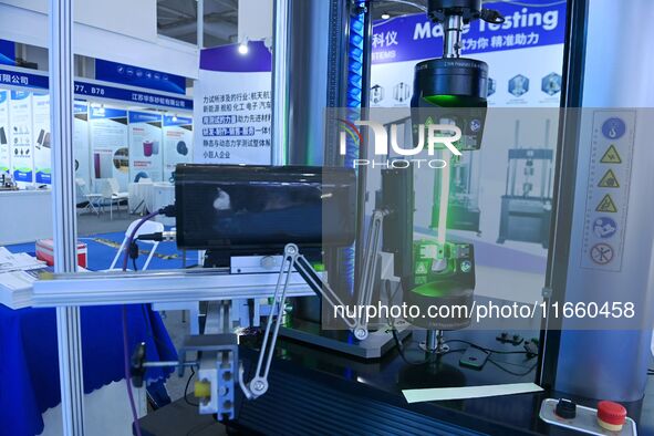 An exhibitor displays mechanical material testing equipment at the 9th China Advanced Materials Industry Expo 2024 in Qingdao, China, on Oct...