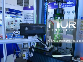 An exhibitor displays mechanical material testing equipment at the 9th China Advanced Materials Industry Expo 2024 in Qingdao, China, on Oct...