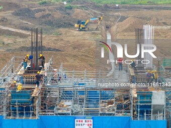 Workers brave the rain as they work at the construction site of the Erhe Junction project of the second phase of the Huaihe River Waterway i...