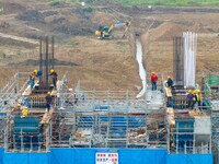 Workers brave the rain as they work at the construction site of the Erhe Junction project of the second phase of the Huaihe River Waterway i...