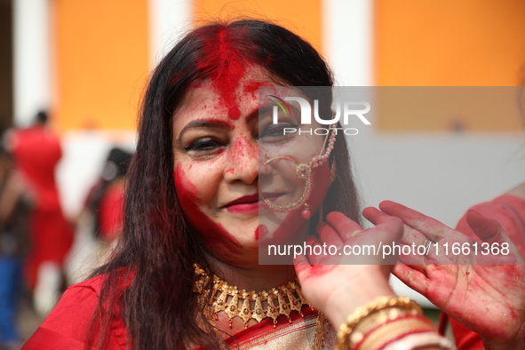 Hindu women apply ''sindhur,'' or vermillion powder, on each other's faces after worshipping the idol of the Hindu goddess Durga before it i...