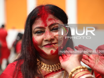 Hindu women apply ''sindhur,'' or vermillion powder, on each other's faces after worshipping the idol of the Hindu goddess Durga before it i...