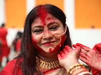 Hindu women apply ''sindhur,'' or vermillion powder, on each other's faces after worshipping the idol of the Hindu goddess Durga before it i...