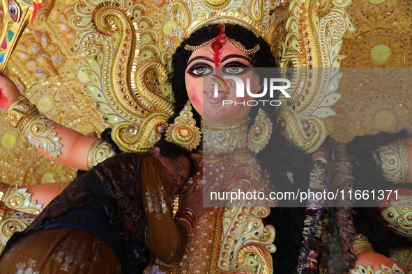 A Hindu woman performs worship of the idol of the Hindu goddess Durga before it is immersed in the Hooghly River during the Durga Puja festi...