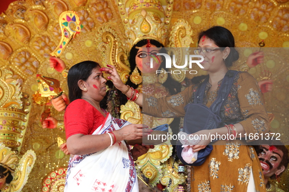 Hindu women apply ''sindhur,'' or vermillion powder, on each other's faces after worshipping the idol of the Hindu goddess Durga before it i...